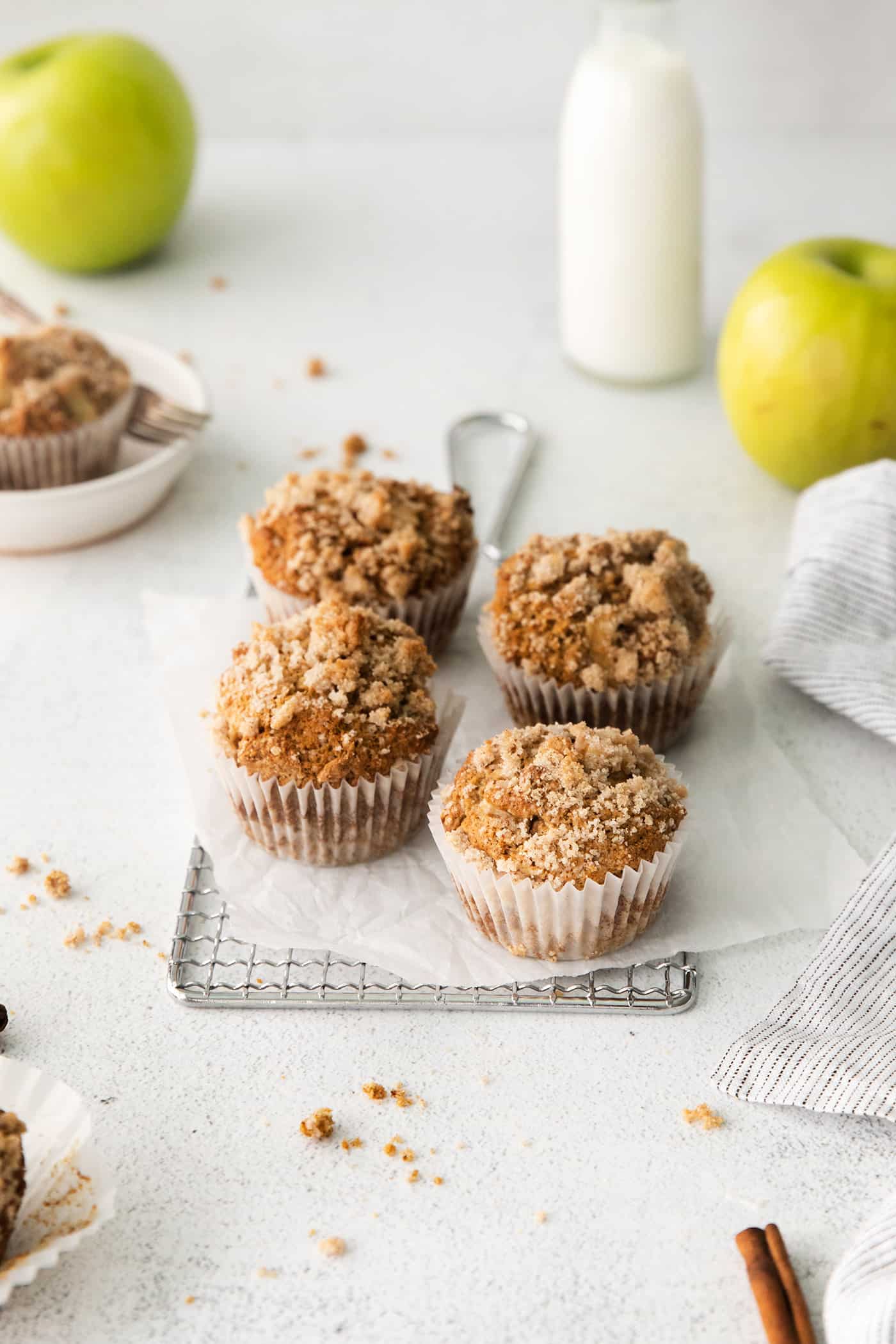 Four apple muffins with cinnamon sugar crumble on a serving tray