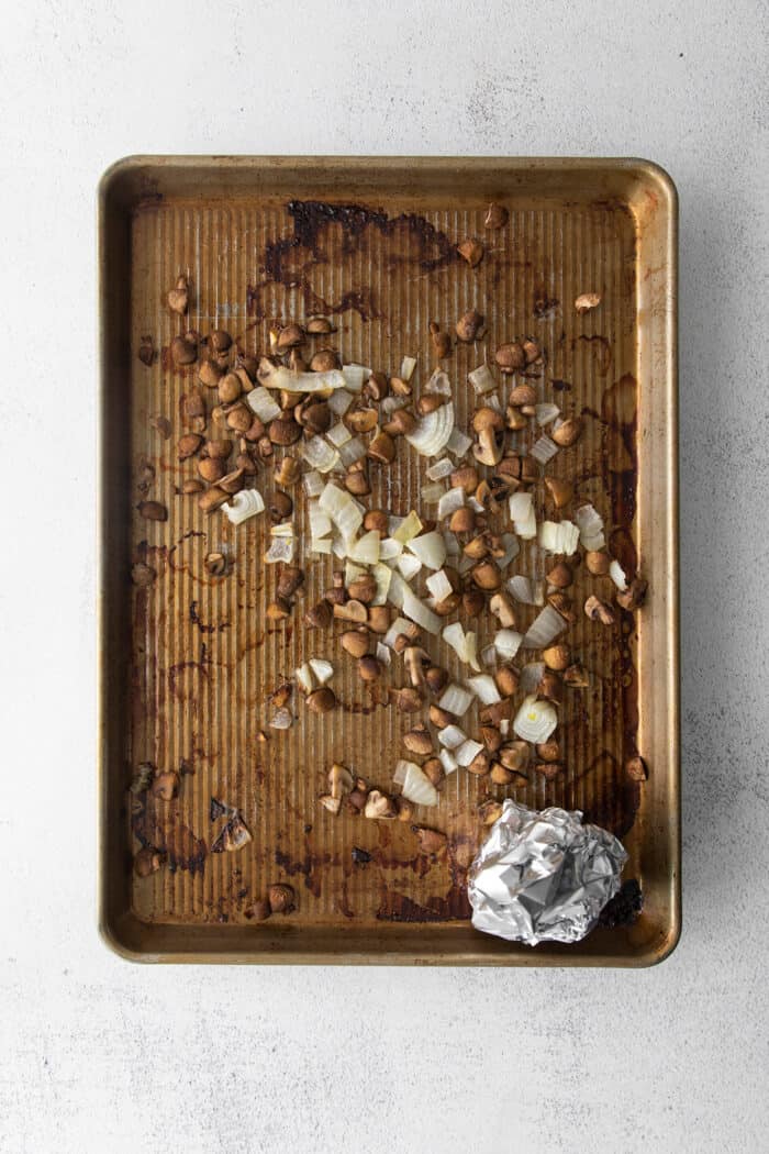 Overhead view of a sheet pan with a roasted garlic clove