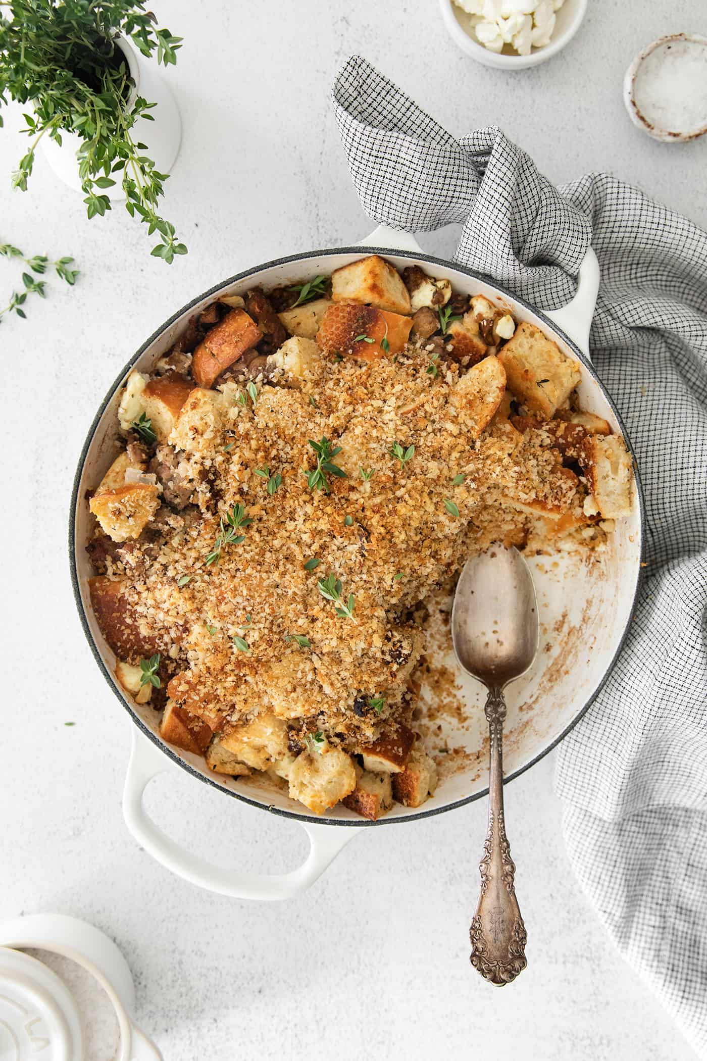 A casserole dish of roasted garlic mushroom dressing with a serving missing