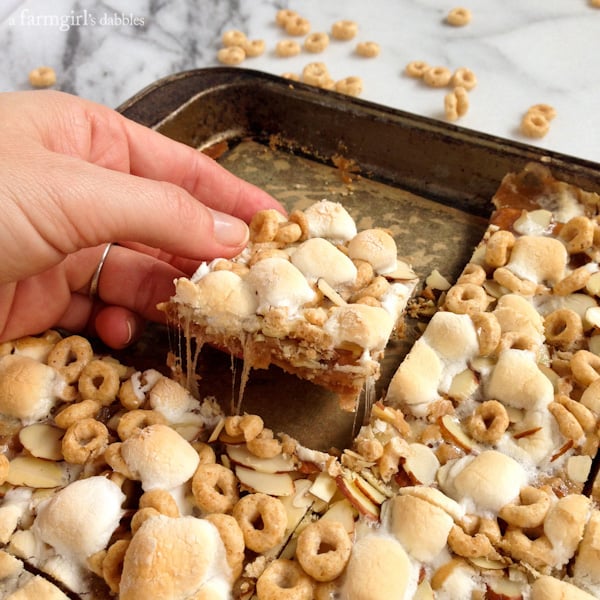 a hand pulling a Caramel Honey Nut Cheerios Square out of a pan