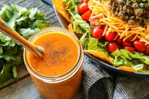 creamy taco salad dressing in a jar, beside fresh taco salad