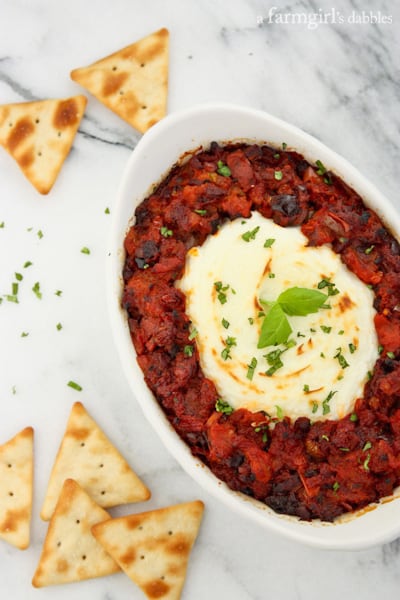 Baked Goat Cheese dip in a white, oval dish served with crackers