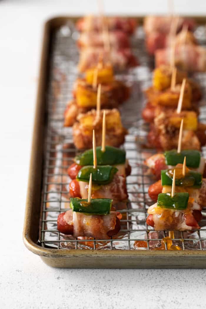 Close-up of bacon wrapped smokies with jalapenos on a baking sheet