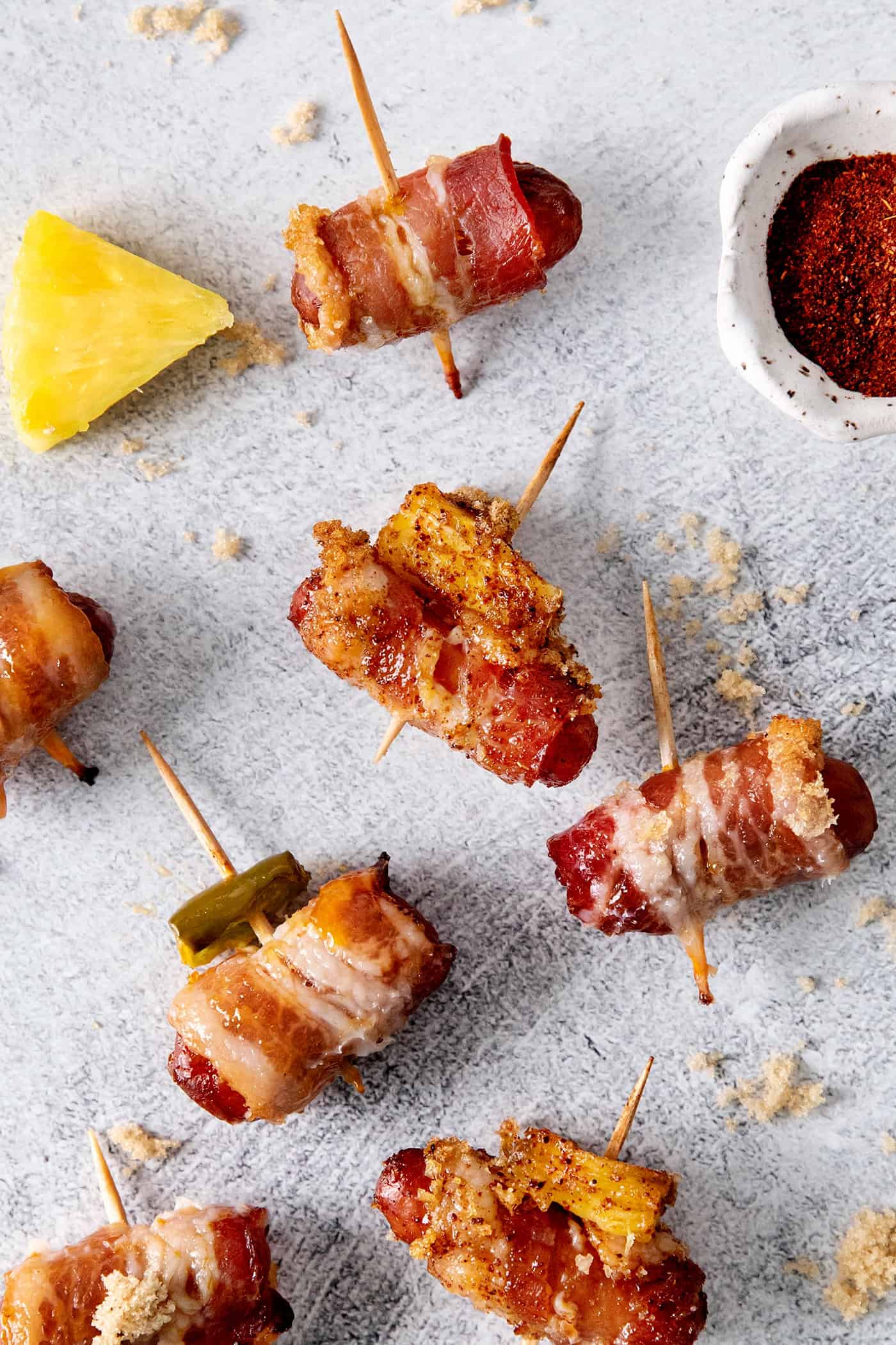 Overhead view of 3 little smokies wrapped in bacon, one with pineapple and one with jalapeno