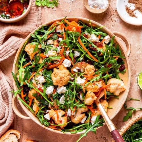 North African cauliflower salad in serving bowl with spoon.