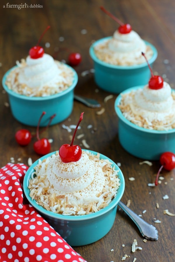 four blue Individual cups of Coconut Tres Leches Cake with whipped cream and cherries