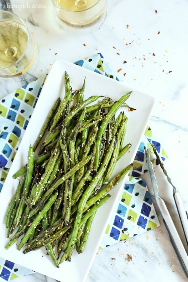 Green Beans on a white platter with tongs