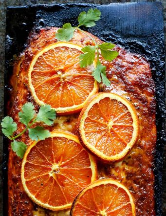 Grilled salmon with orange slices on a charred plank