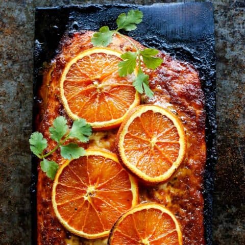 Grilled salmon with orange slices on a charred plank