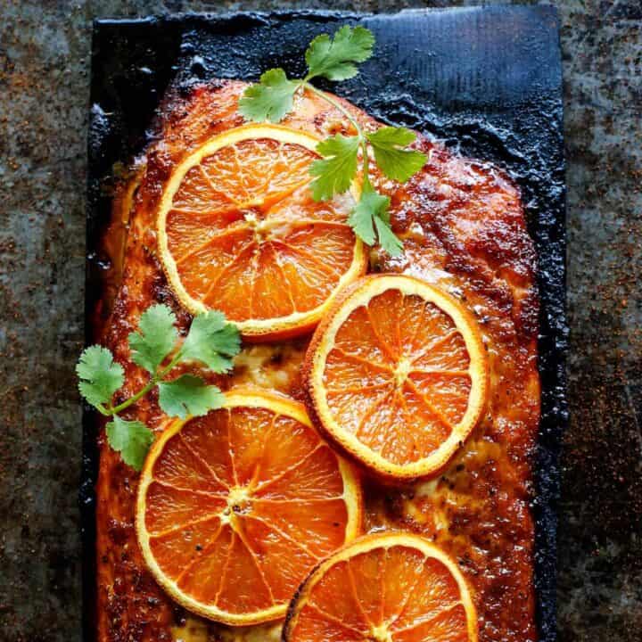 Grilled salmon with orange slices on a charred plank