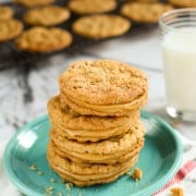 Peanut Butter Sandwich Cookies stacked on blue plate with a glass of milk