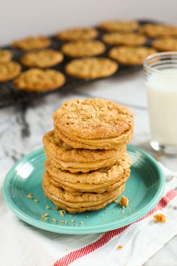 Peanut Butter Sandwich Cookies stacked on blue plate with a glass of milk