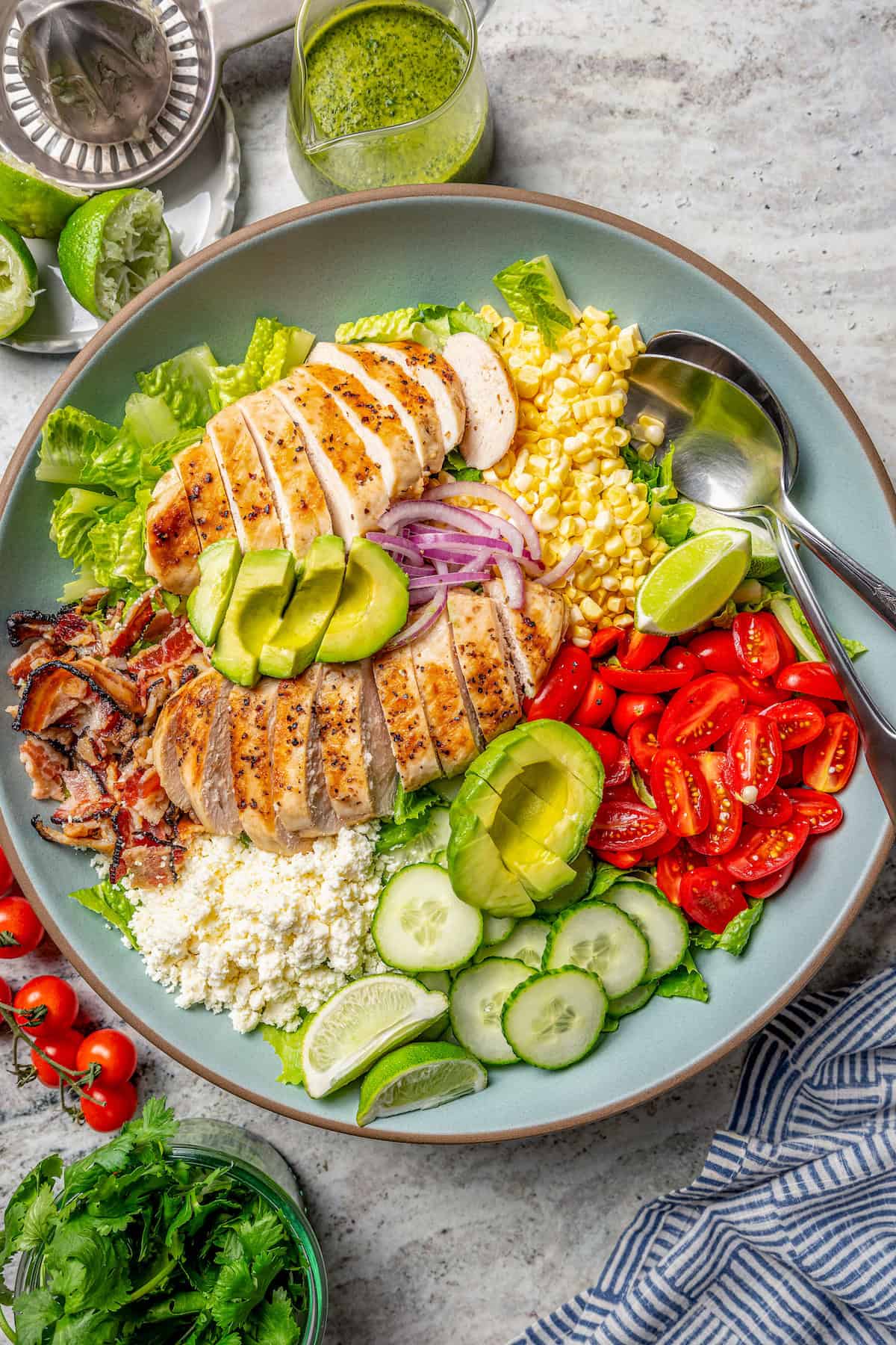 This Grilled Chicken Salad combines fresh corn, creamy avocado and juicy tomatoes with a zippy cilantro-lime vinaigrette for one tasty salad! Overhead view of grilled chicken salad in bowl with two spoons