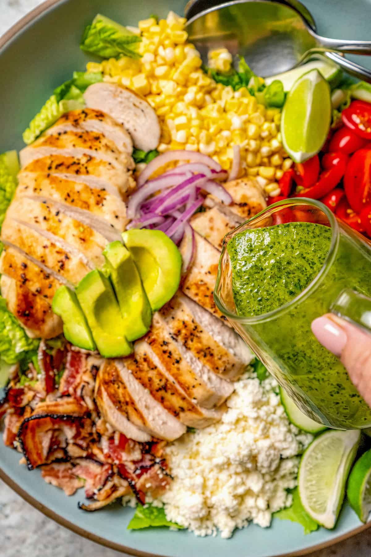 Pouring cilantro lime vinaigrette onto grilled chicken salad