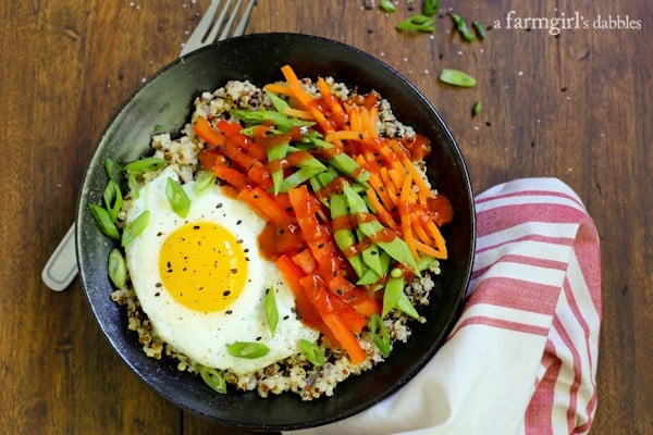 a black bowl of Lemon Quinoa with vegetables, eggs, and sriracha sauce