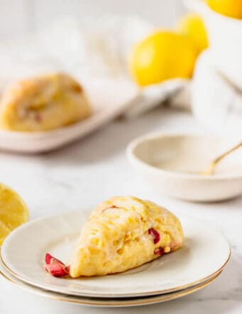 A lemon scone on a plate with another in the background