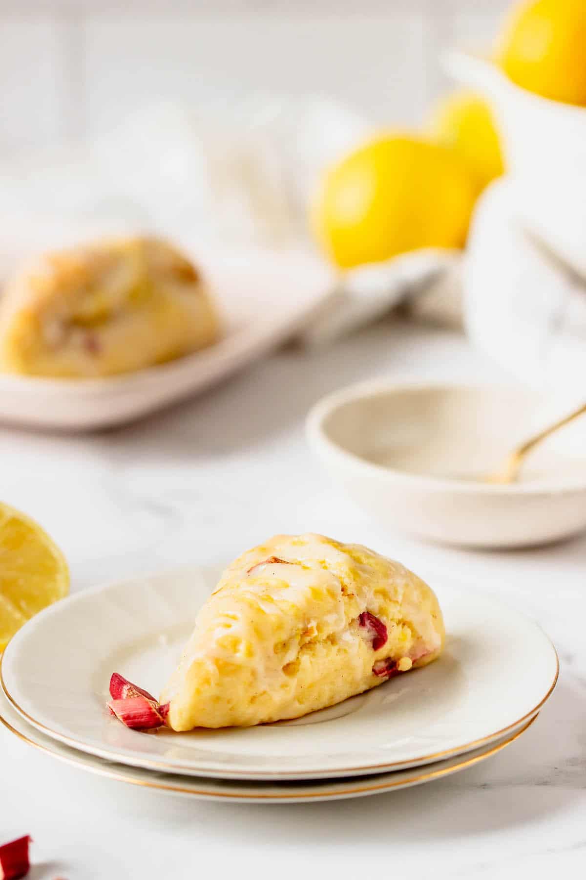 A lemon scone on a plate with another in the background