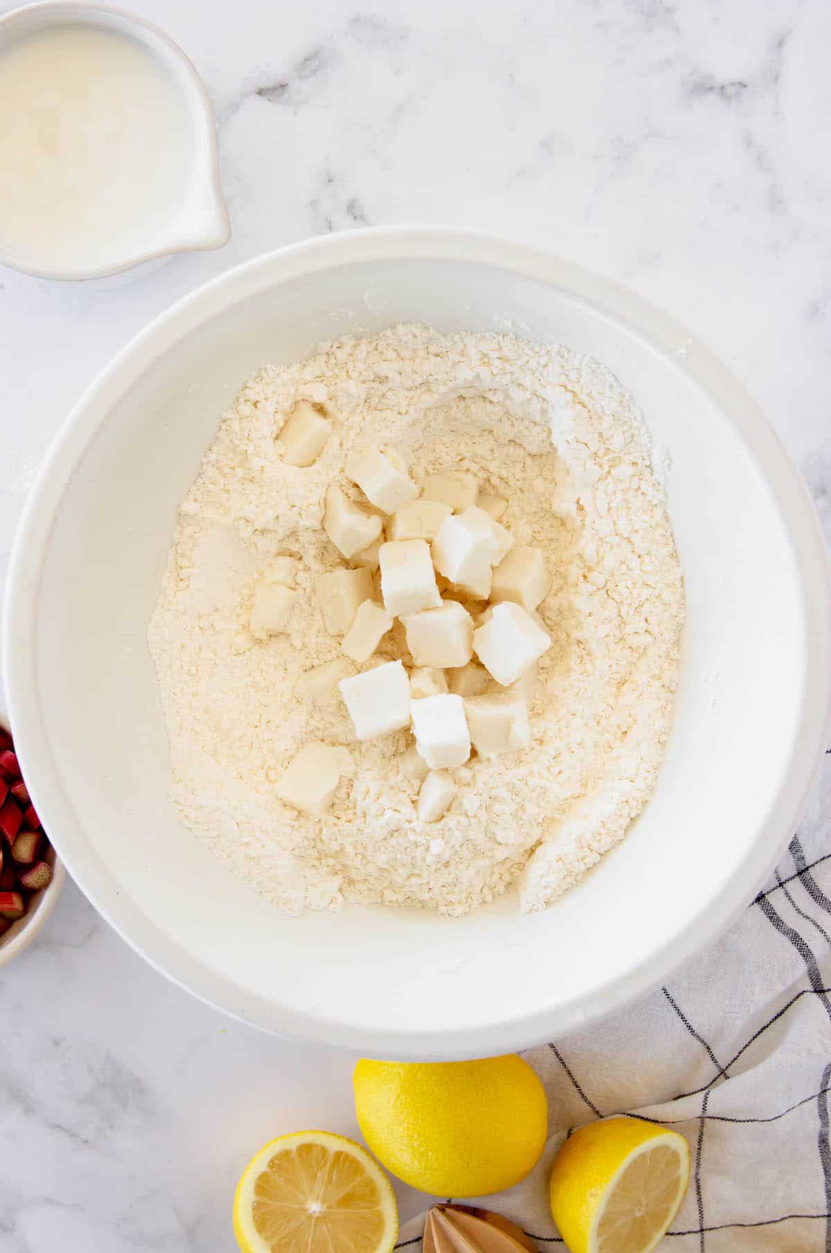 Flour mixture in a white bowl with chopped cold butter