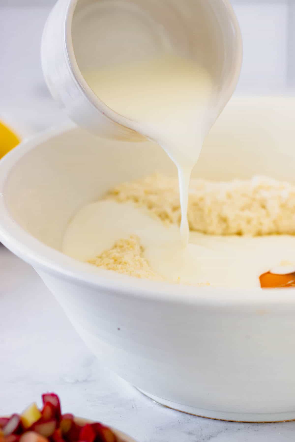 Milk being poured into a white mixing bowl