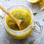pinterest image of herby lemon vinaigrette in a jar with fresh lemon in the background