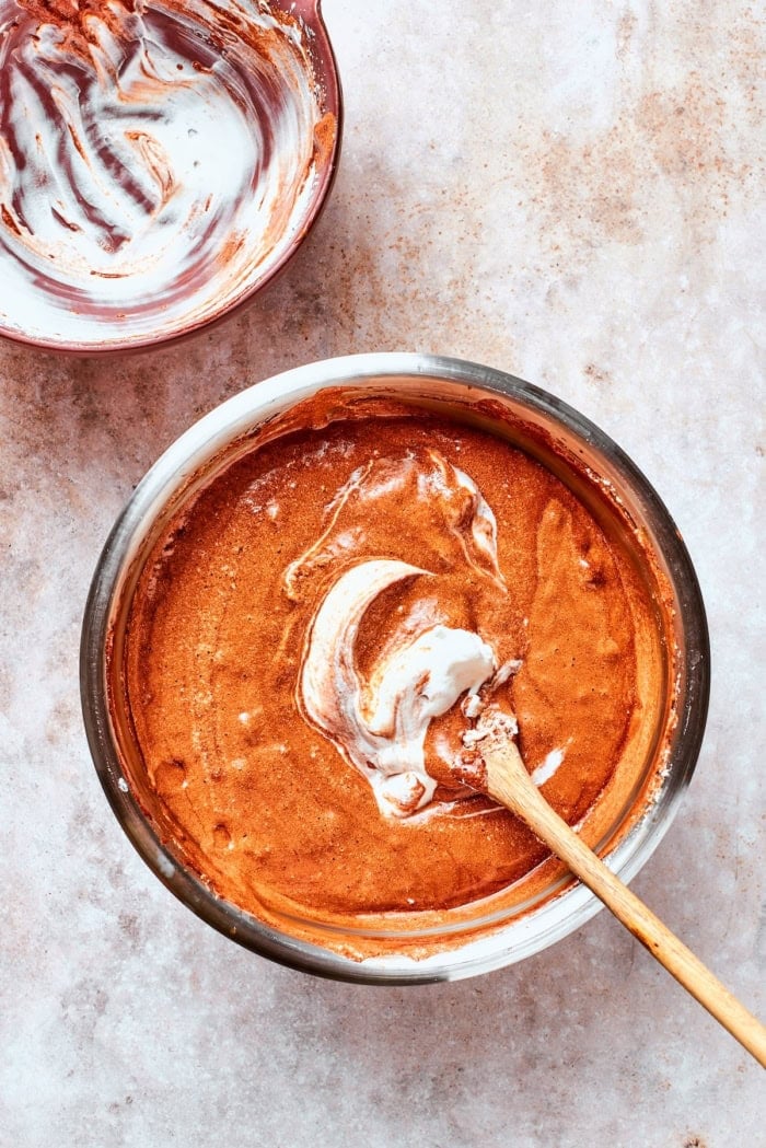 Folding chocolate and egg white mixture together in bowl.