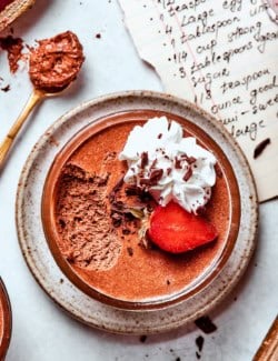 Spoonful of chocolate mousse set next to mousse cup.