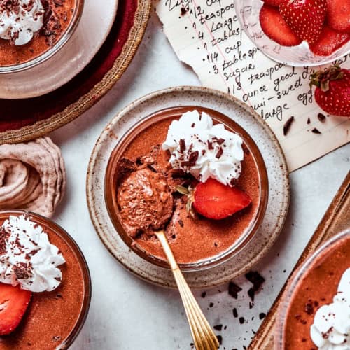 Chocolate mousse cups with whipped cream, strawberry, and chocolate shavings.
