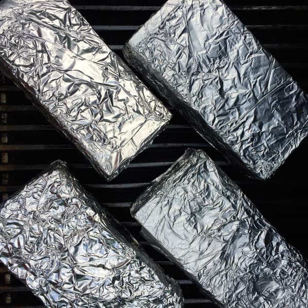 Four bricks wrapped in foil on a grill