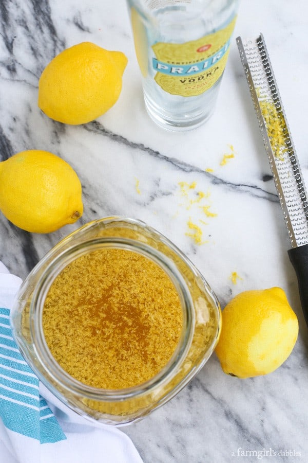 a glass jar of limoncello with fresh lemons and lemon zest