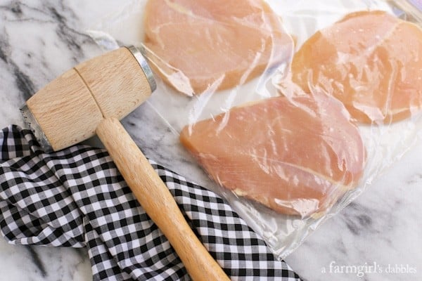 chicken breasts in a clear bag with a kitchen mallet
