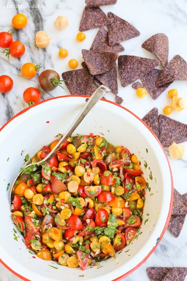 a white bowl of Ground Cherry Salsa with blue corn tortilla chips