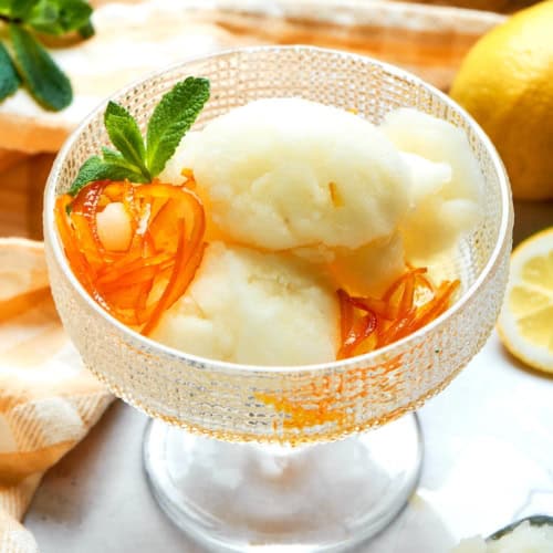 Glass cup of lemon sorbet with candied orange peel and fresh mint.