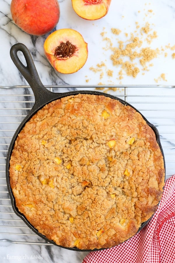 Peach Streusel Coffee Cake in a Skillet on a cooling rack with fresh peaches
