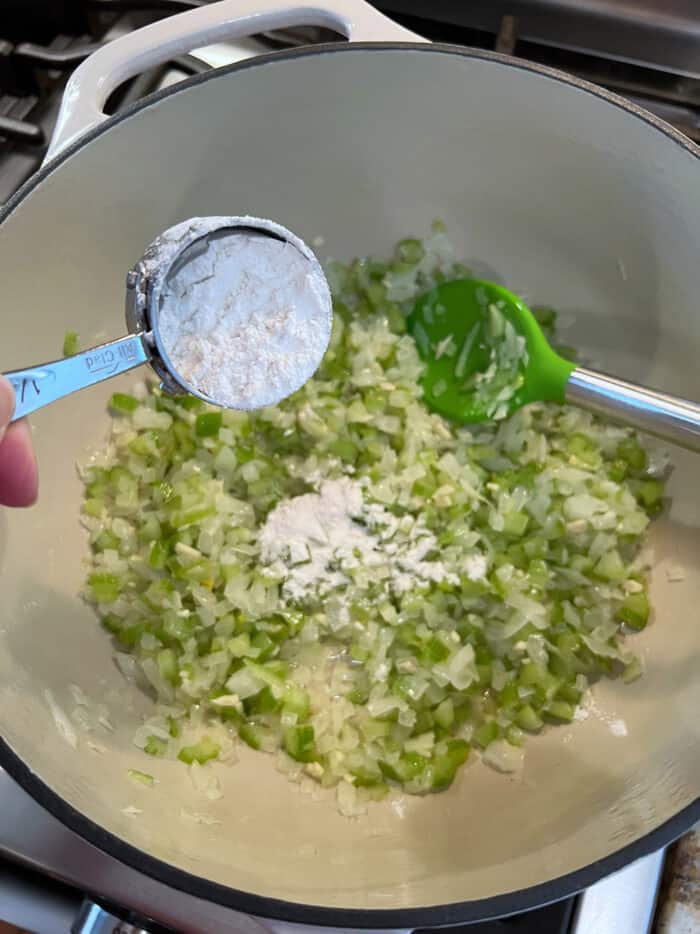 Flour being added to sauteed scallions and garlic