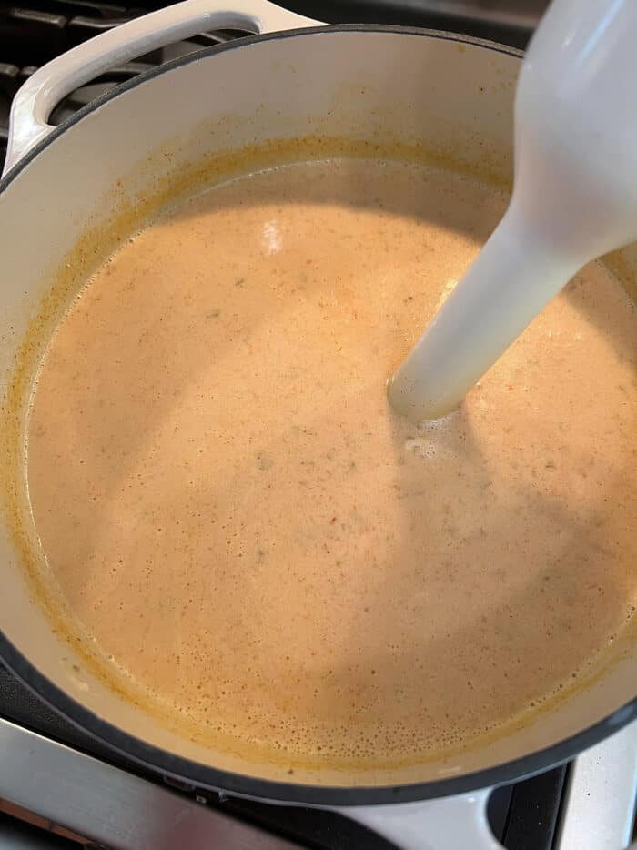 A spoon stirring crab bisque broth