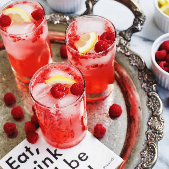 3 glasses of raspberry smash, garnished with lemon and fresh raspberries