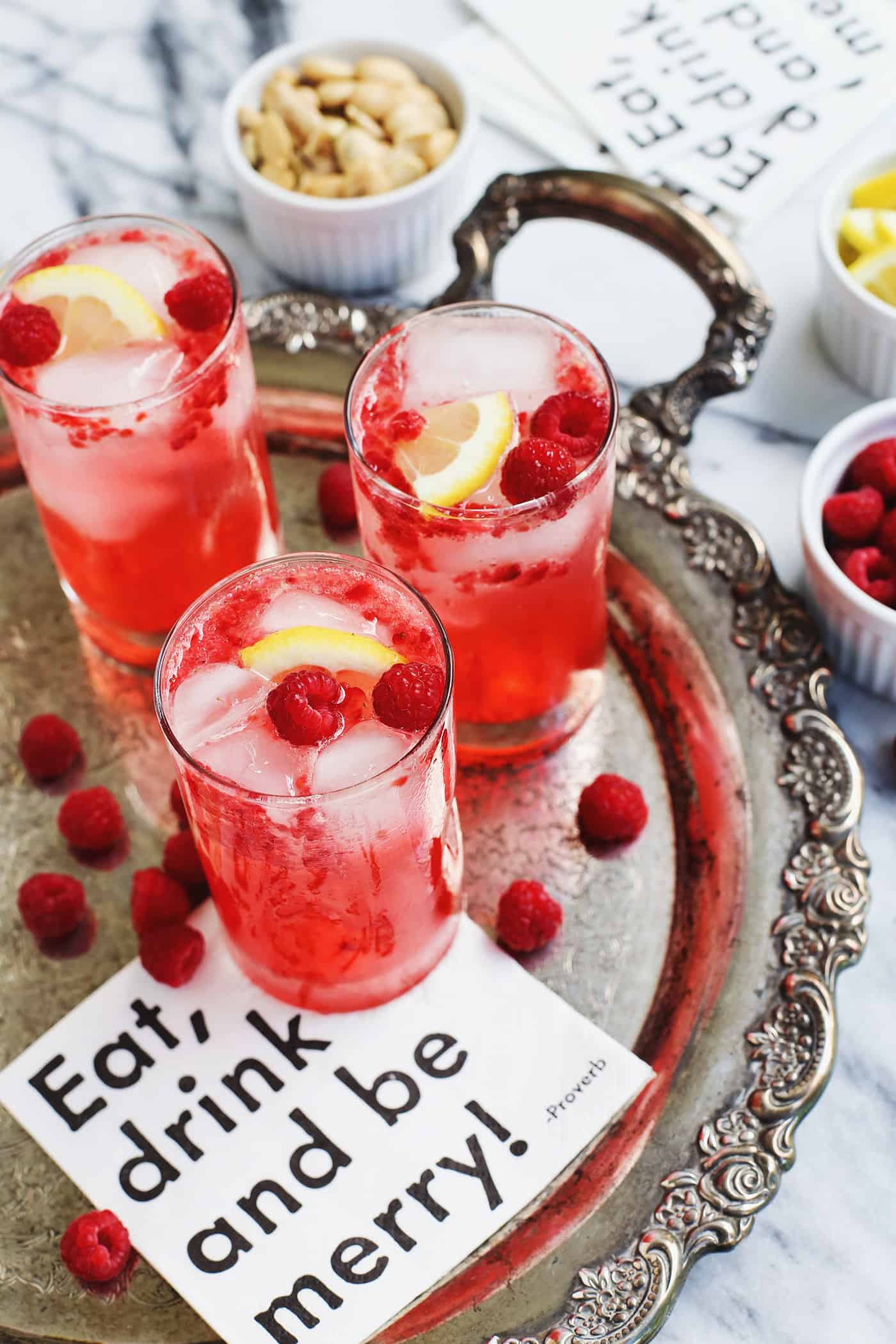 3 glasses of raspberry smash, garnished with lemon and fresh raspberries