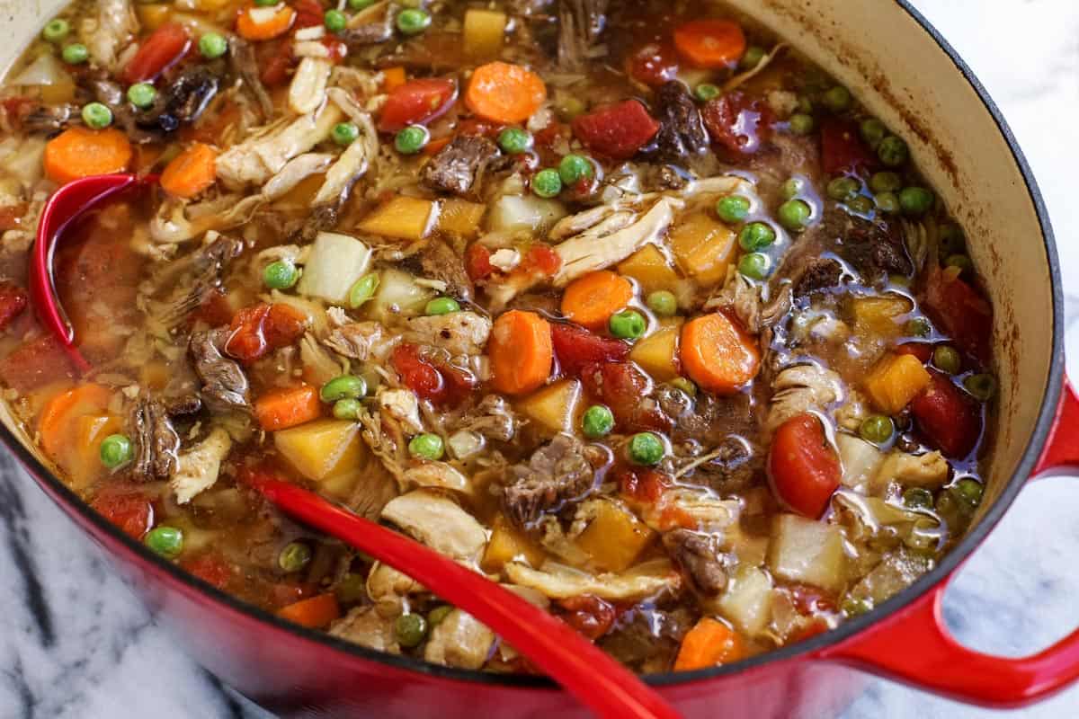 a large red pot of soup with vegetables and meats