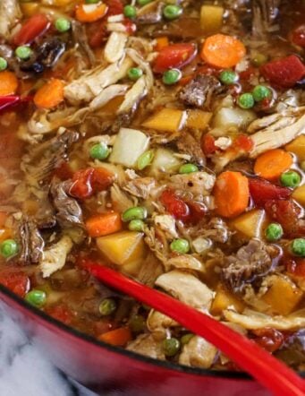 booya stew in a red pot with a red ladle