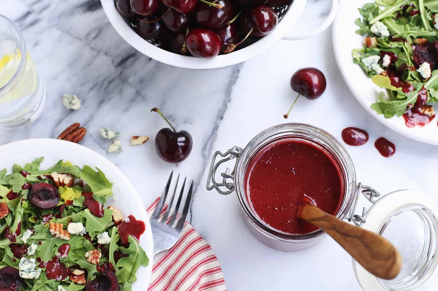 A jar of cherry vinaigrette and two salads