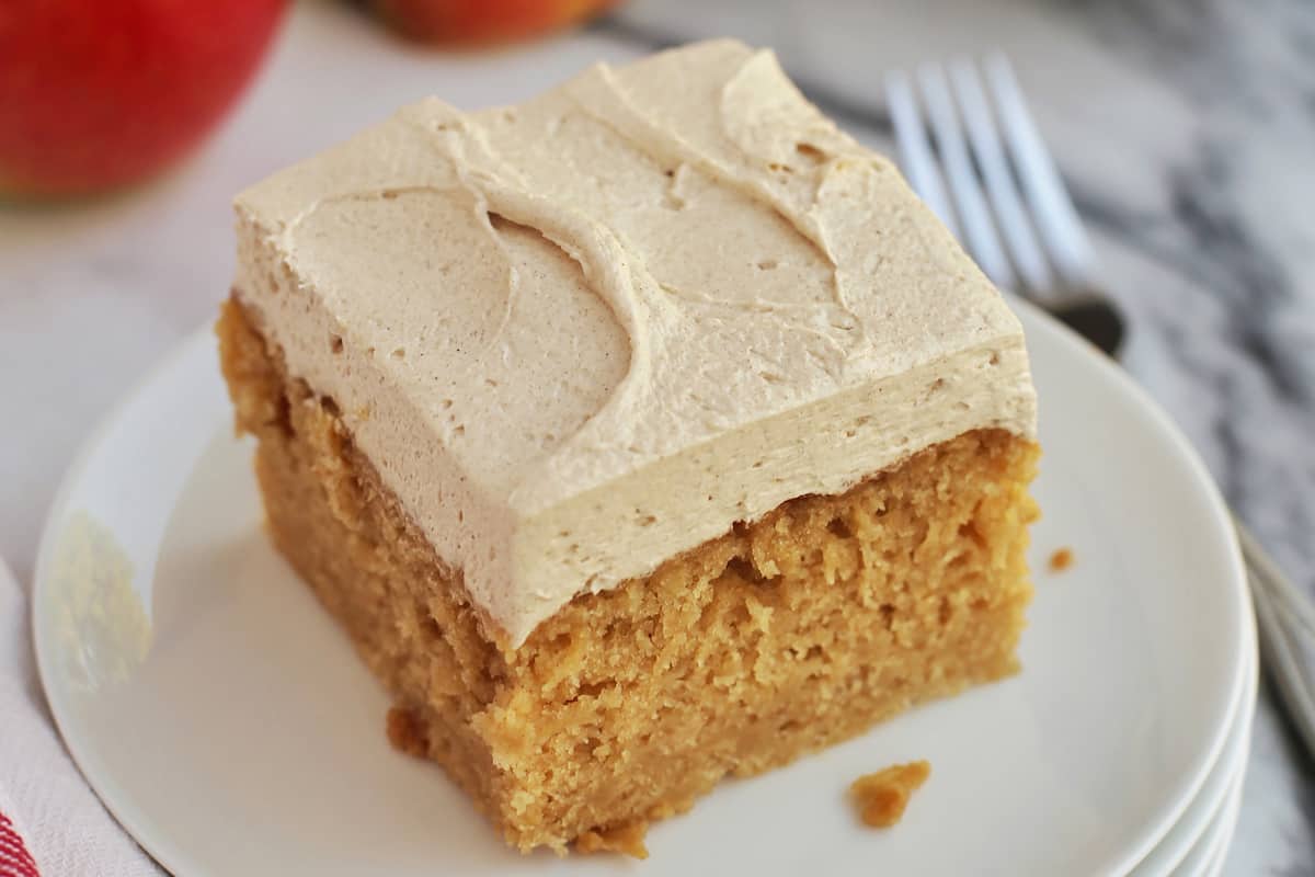 A slice of frosted apple cake on a plate