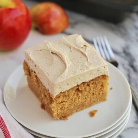 A slice of frosted apple cake on a plate