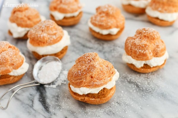 Homemade Cream Puffs on a table with a spoon of powdered sugar