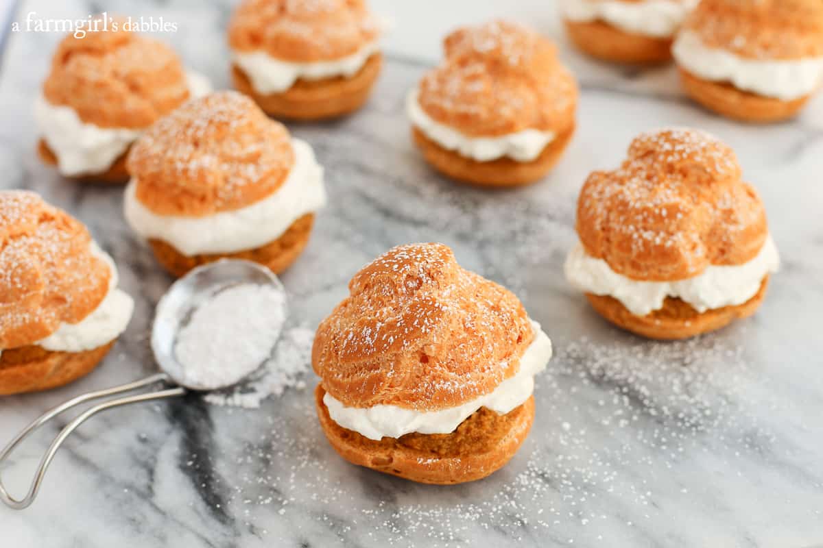 Homemade Cream Puffs on a table with a spoon of powdered sugar.