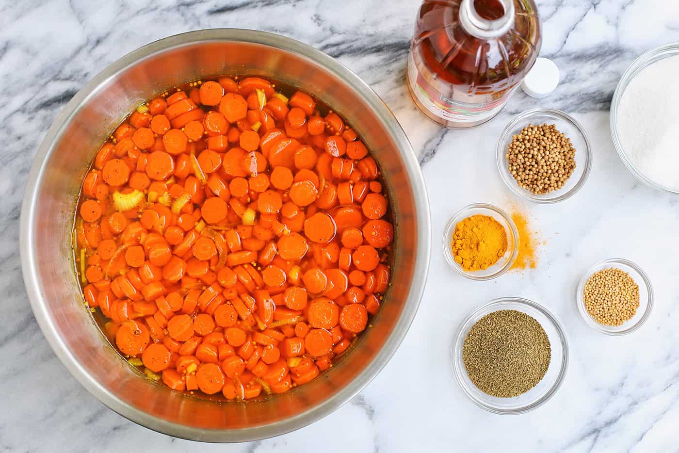 Sliced carrots and onions in a pan and seasonings measured out