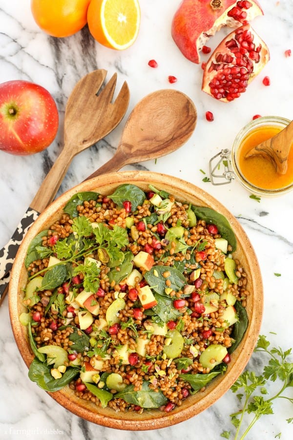 Wheat Berry and Spinach Salad in a large, pottery bowl with wooden serving spoons