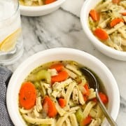 Classic chicken noodle soup in a white bowl with a spoon