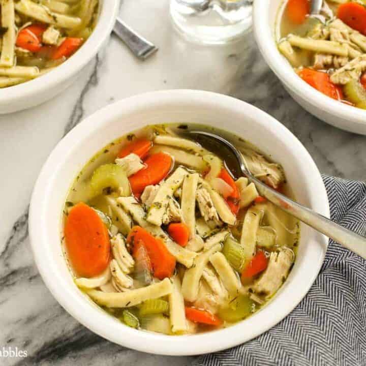 A white bowl filled with homemade chicken noodle soup