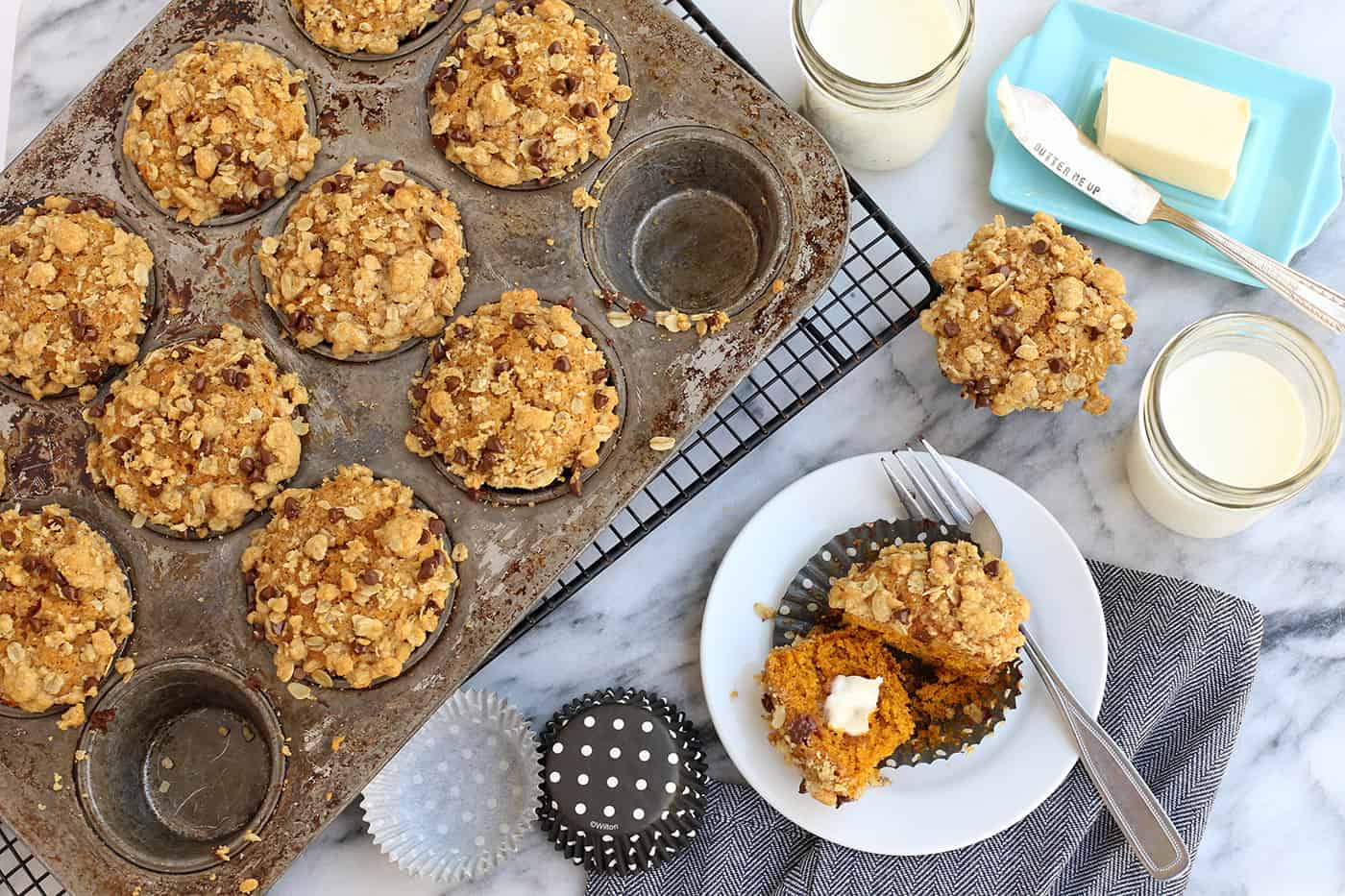 Pumpkin muffins with streusel topping in a muffin pan and one in a bowl