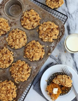 Pumpkin muffins with oatmeal chocolate chip streusel in a muffin pan with one in a dish to serve